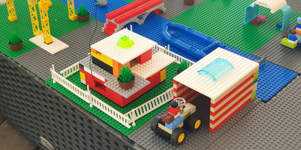 Eine Lego-Stadt mit Fluss, Brücke, Haus, Traktor+Garage, Kran und Bus
