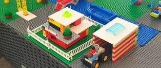 Eine Lego-Stadt mit Fluss, Brücke, Haus, Traktor+Garage, Kran und Bus
