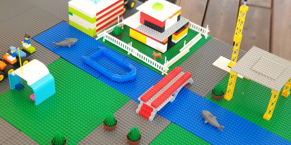 Eine Lego-Stadt mit Fluss, Brücke, Haus, Traktor+Garage, Kran und Bus
