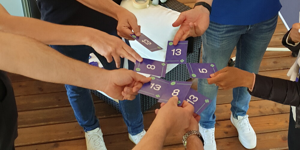 Sieben Hände halten Spielkarten mit Nummern in die Mitte